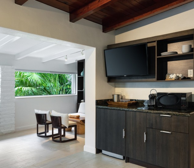 entrance of bungalow begins with a small kitchen area that has a microwave and a mounted tv stand