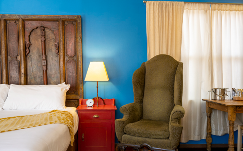 a hotel room with a bed and an armchair by the night stand table with a lamp