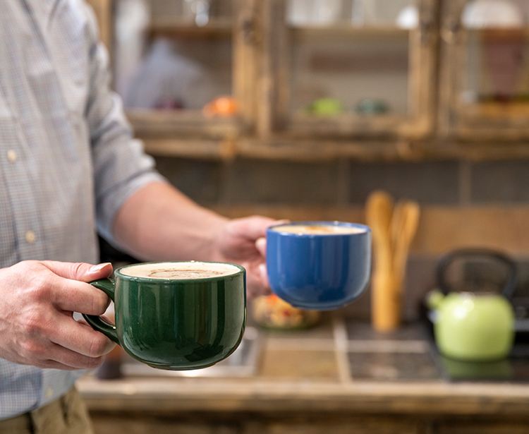 a man walking with two mugs of coffee