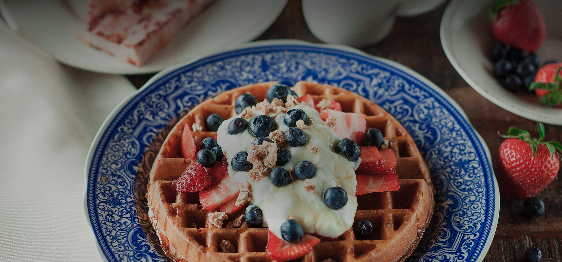 a waffle topped with whipped cream and fresh strawberries and blueberries