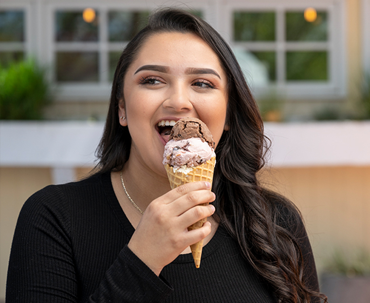 a woman eating an ice cream cone outside