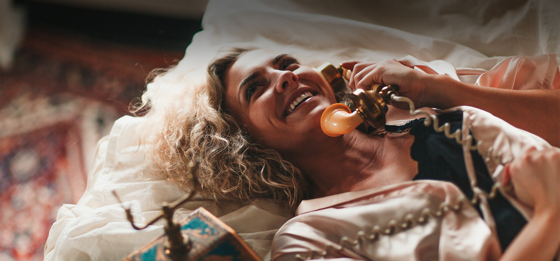 a smiling woman talking on a phone while laying down