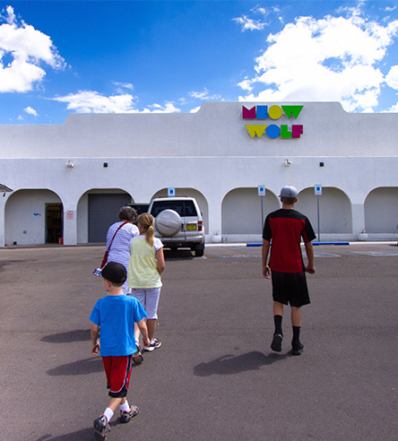 a family walking towards a building that has a colorful sign on it during the day