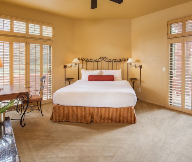 Internal view of a big room with a large bed, a desk and an electric fireplace