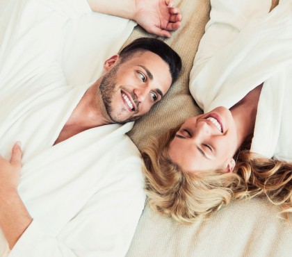 Top view of a couple laying on a bed, wearing a bathrobe