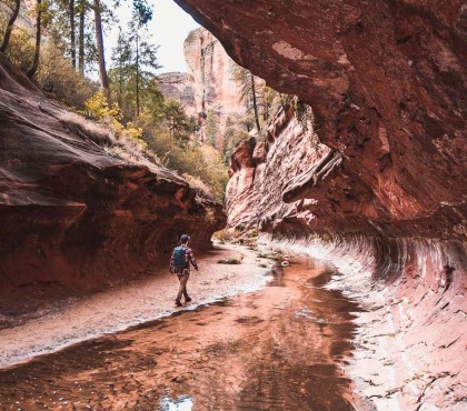 View of a man walking through a cave, next to a little river