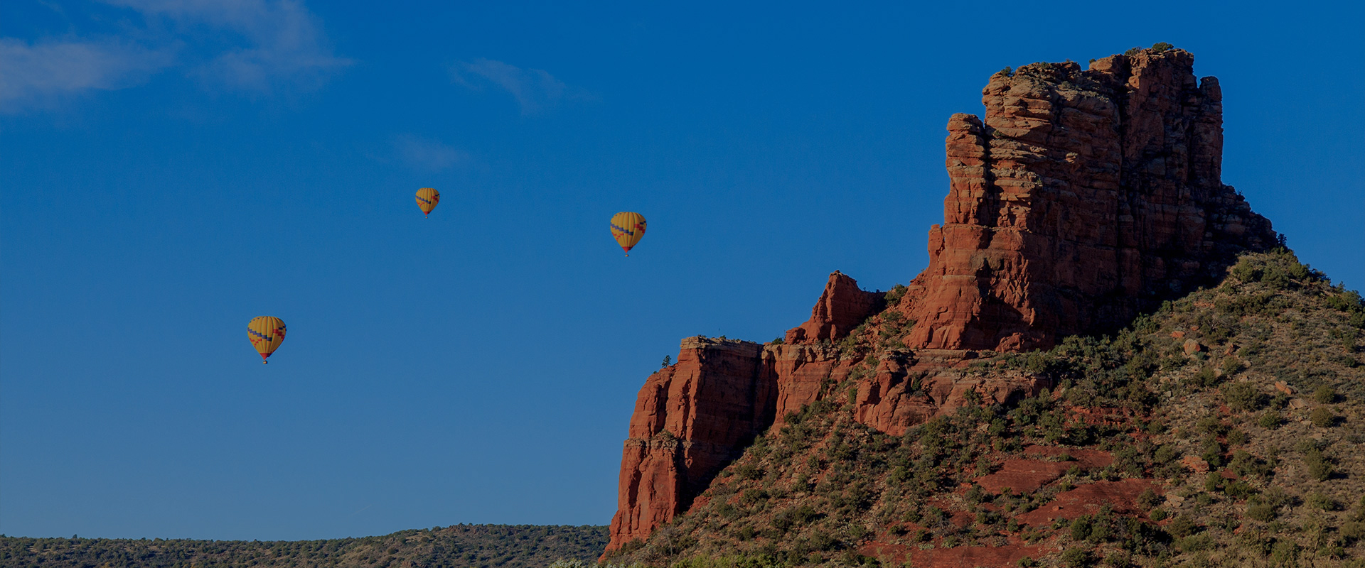 yellow hot air balloons floating near large rock formation