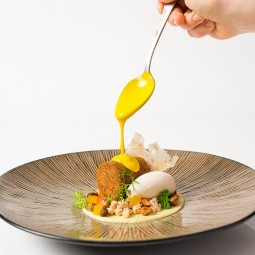 chef pouring a yellow sauce over the food