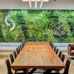 long wooden table with a green leaved wall behind it