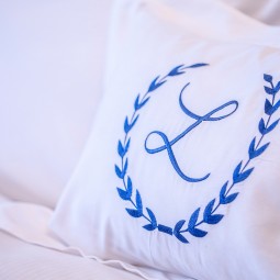 white pillow with the letter L in blue and leaves