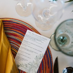 table set with a colorful place mate and napkin, 3 drink glasses, flatware, and menu