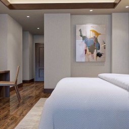 a king bed within a modern room that has wooden furniture and floors