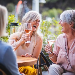 3 older ladies laughing and enjoying some wine