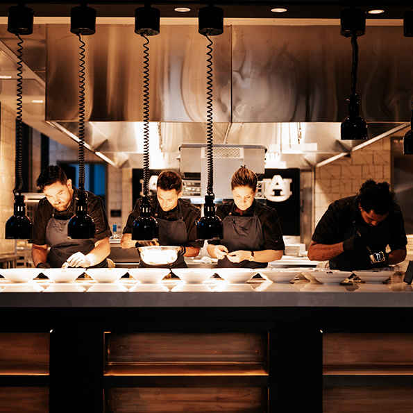 chefs plating food in a kitchen