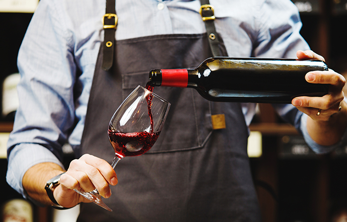 someone pouring wine into a wine glass