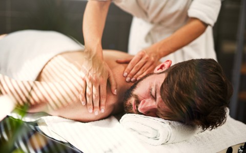 view of a man laying on his stomach receiving a back massage