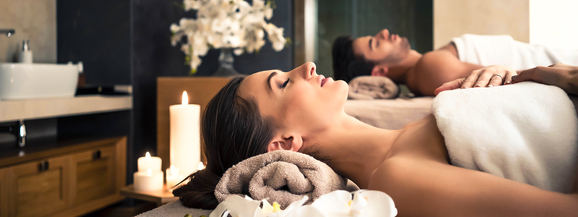side view of a man and woman laying in spa beds