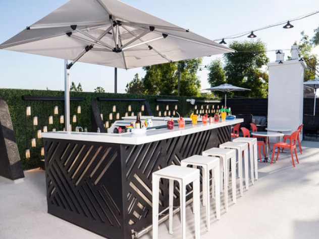outdoor bar at the pool in front of a wall of greenery with colorful drinks lined up