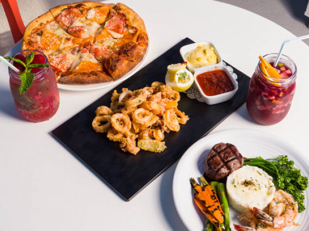 al fresco dining at the pool area with calamari pizza a shrimp and steak dish and two cocktails