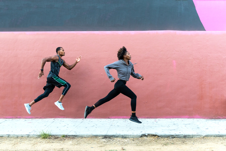 athletic runners leaping in front of urban wall