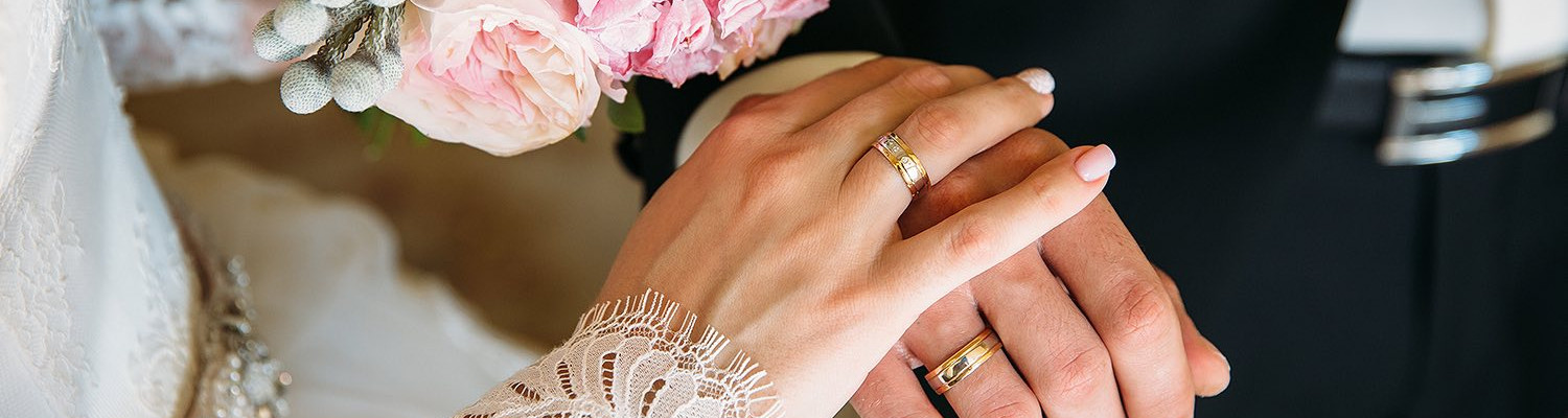 Close up of bride and grooms hands touching wearing wedding rings