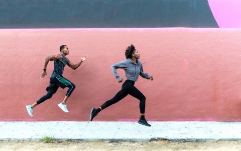 athletic runners leaping in front of urban wall