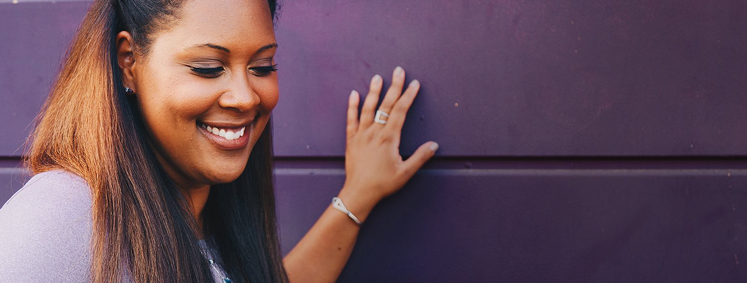 Woman standing against purple wall