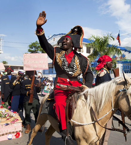 Man riding horse down street during dessalines day