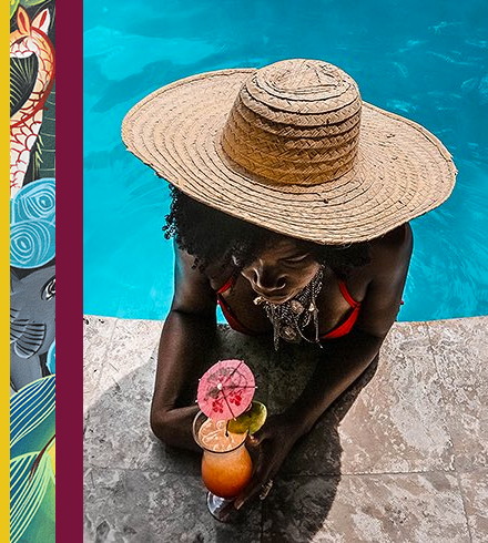 Woman at pool wearing sunhat and holding cocktail