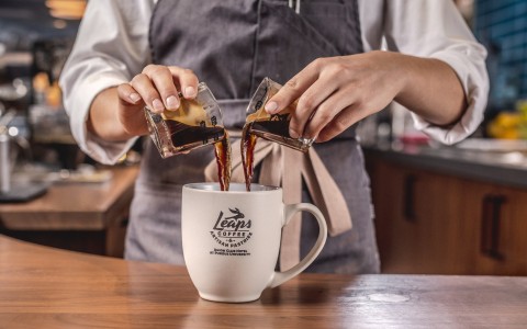 Barista pouring in two glasses of espresso into a Leaps coffee mug