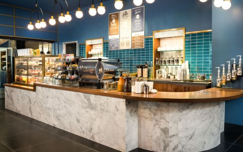 Coffee counter at Leaps with marble backsplash, blue tile wall, and several coffee bar offerings