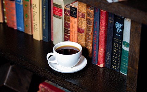 coffee mug placed on bookshelf in front of books