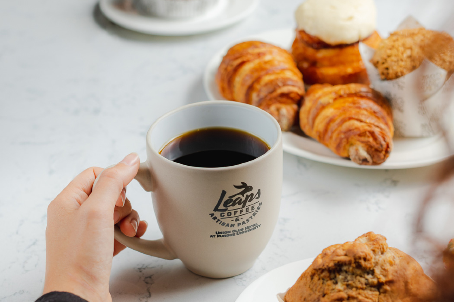 coffee cup with pastry behind it