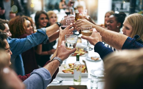 large table with people cheering with their wine glasses