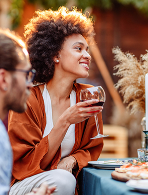african american woman holding a glass of wine next to some of her friends