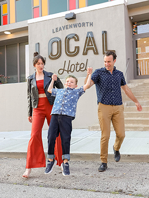 a couple composed by a woman and a man playing with a kid in front of the entry