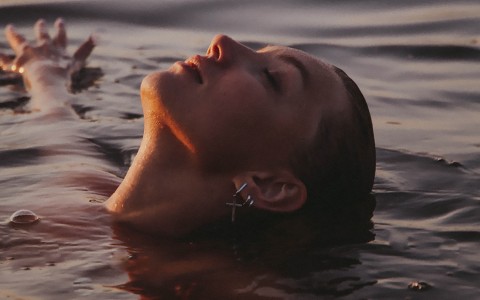relaxed woman floating on her back in serene water at sunset