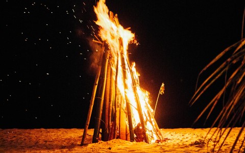 large tall bonfire crackling on the beach at night