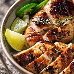 savory grilled chicken breast sliced in a bowl with lime wedges
