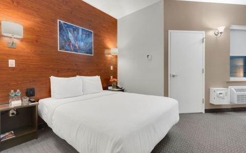 cozy queen bedroom with white comforter and wood headboard