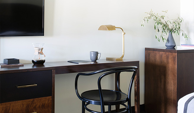 sleek dark wood desk and chair below mounted tv and next to dresser unit