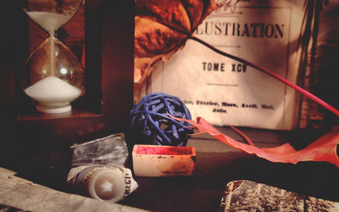 Hourglass with sand falling with picture tube of paste ball of string and clue in background