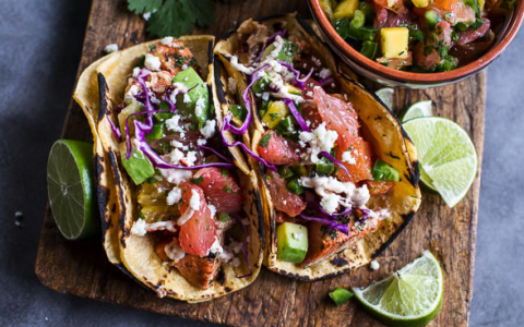 fresh tacos in tortilla on wood cutting board surround by lime wedges