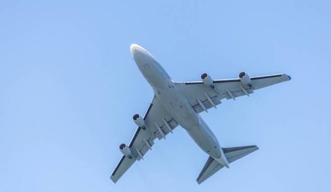 Underside of a jet flying against a blue sky