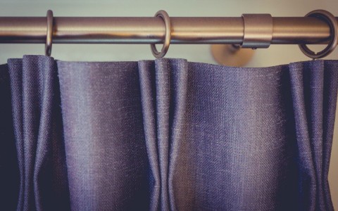 detail shot of grey curtains on bronze curtain rod