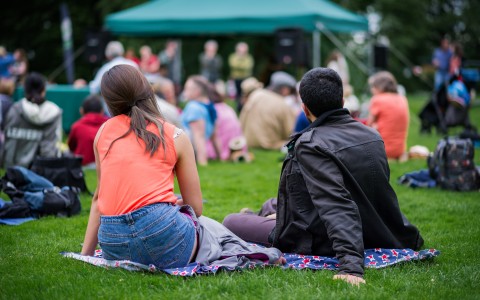 man and women sitting on a blanket at an outdoor gathering