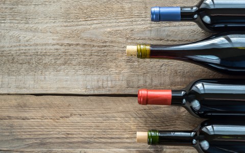 tops of wine bottles on a wooden table