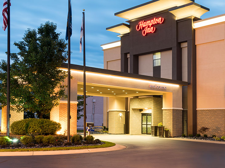 Dark brown building with Hampton Inn logo lit up at night