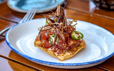Ahi tuna dish placed on a crisp and topped with jalapeno and other garnishes