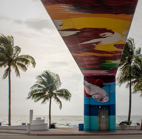 Under view of painted fish mural bridge on the beach with palm trees